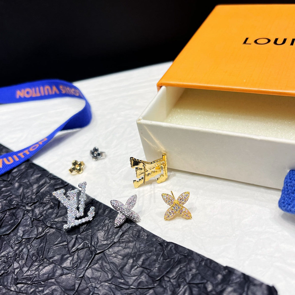 Asymmetrische Strass-Ohrringe mit Blumenlogo