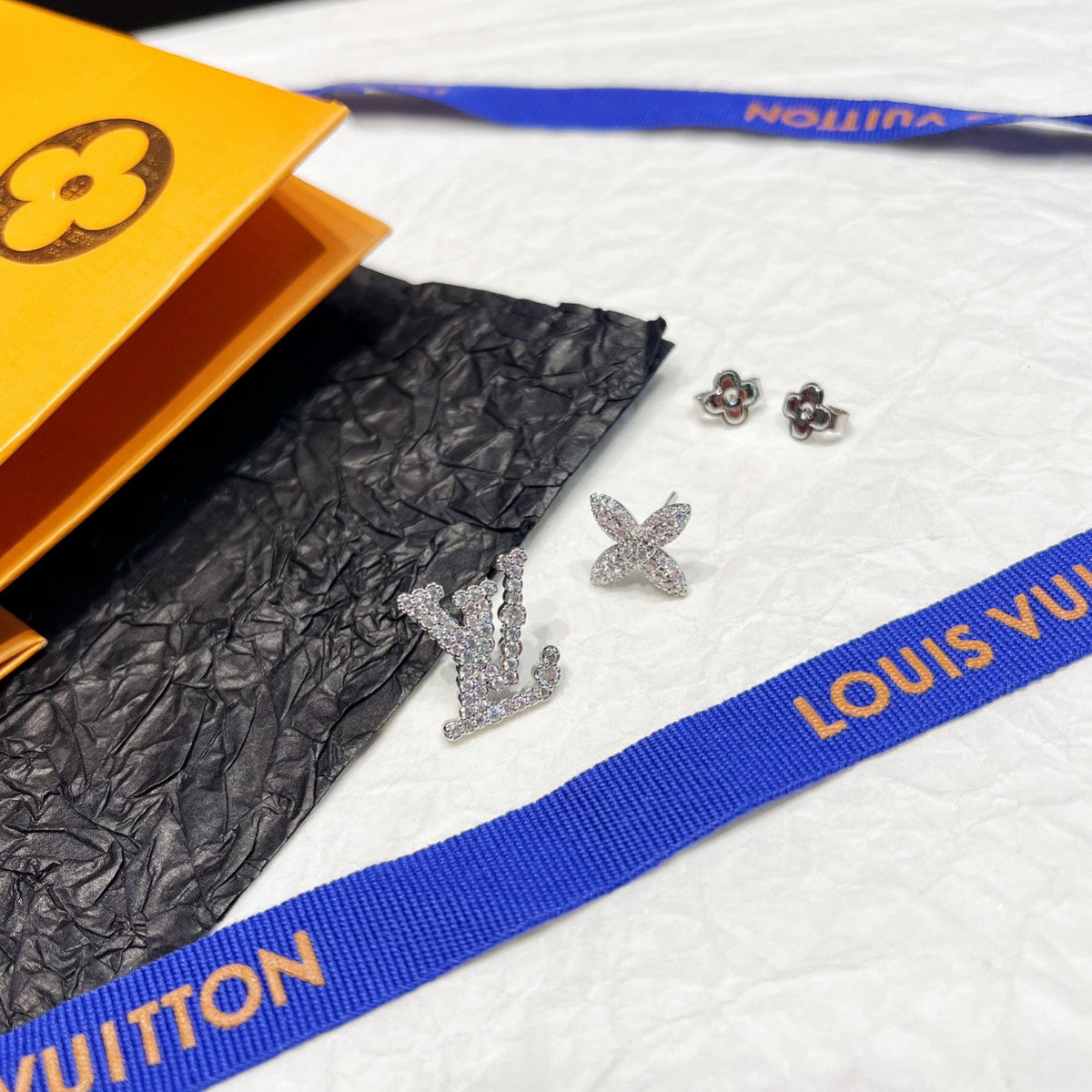 Asymmetrische Strass-Ohrringe mit Blumenlogo
